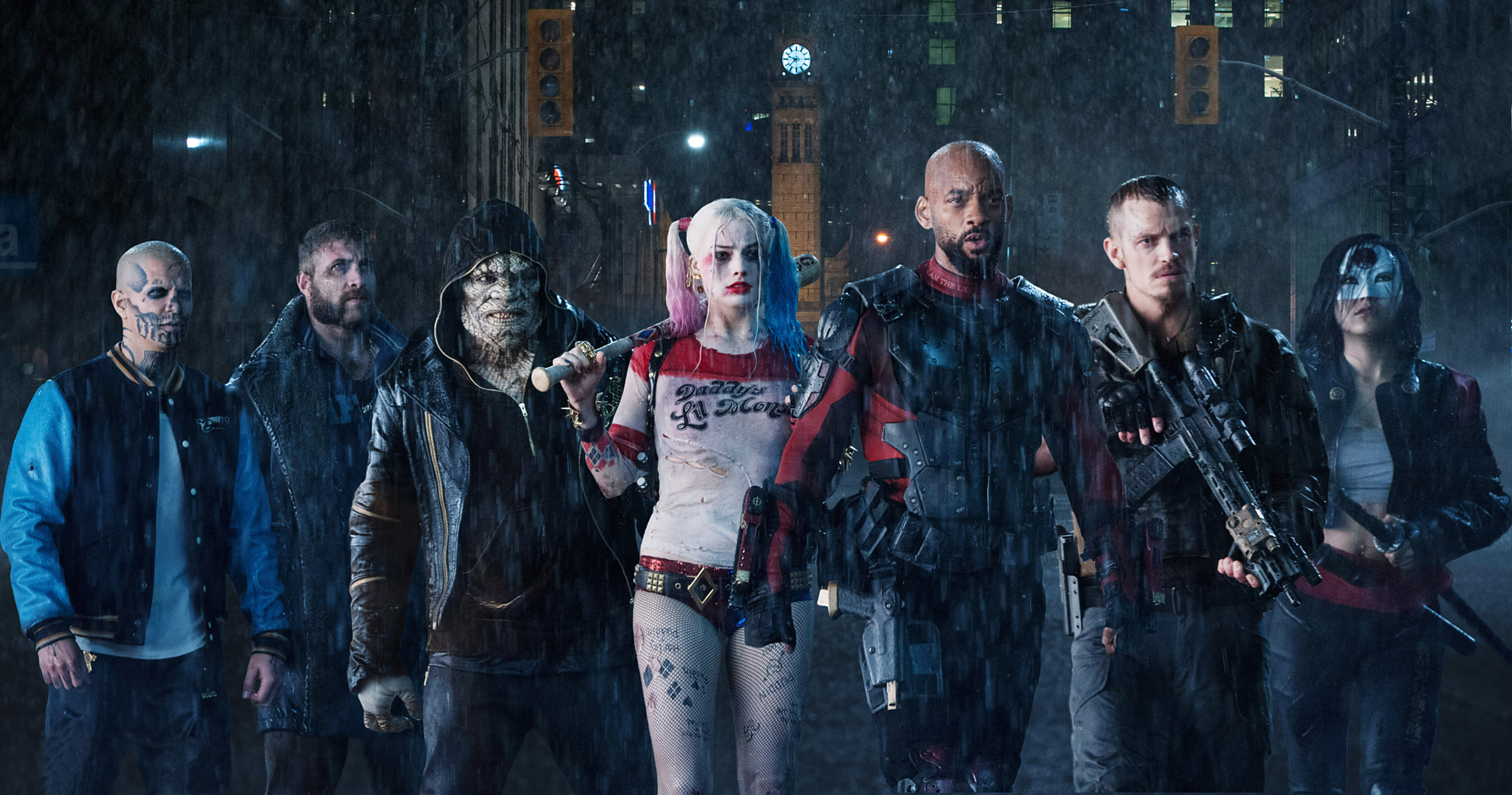A group of people dressed as characters from the film Suicide Squad, including Harley Quinn, standing in the rain at night