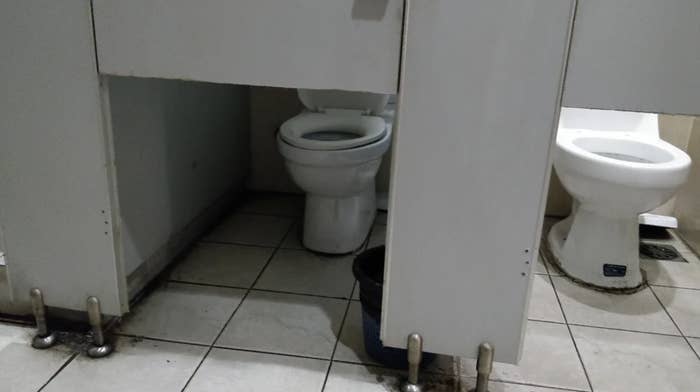 Public restroom with two toilet stalls, but the stall doors don&#x27;t cover the toilet