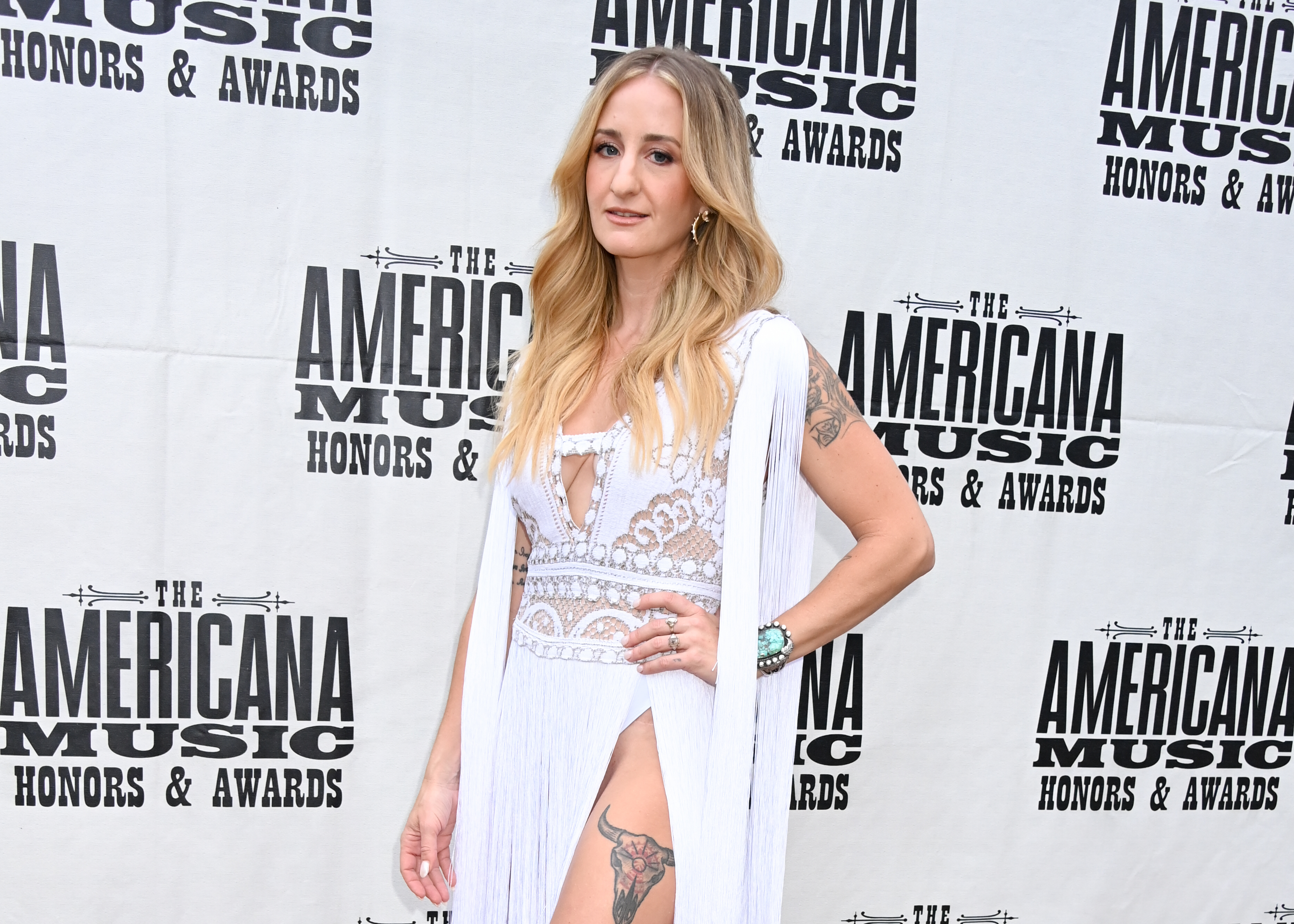 Woman in a white lace dress stands at the Americana Music Honors & Awards event
