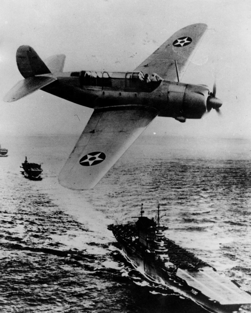 Vintage photo of a fighter plane flying over a warship at sea