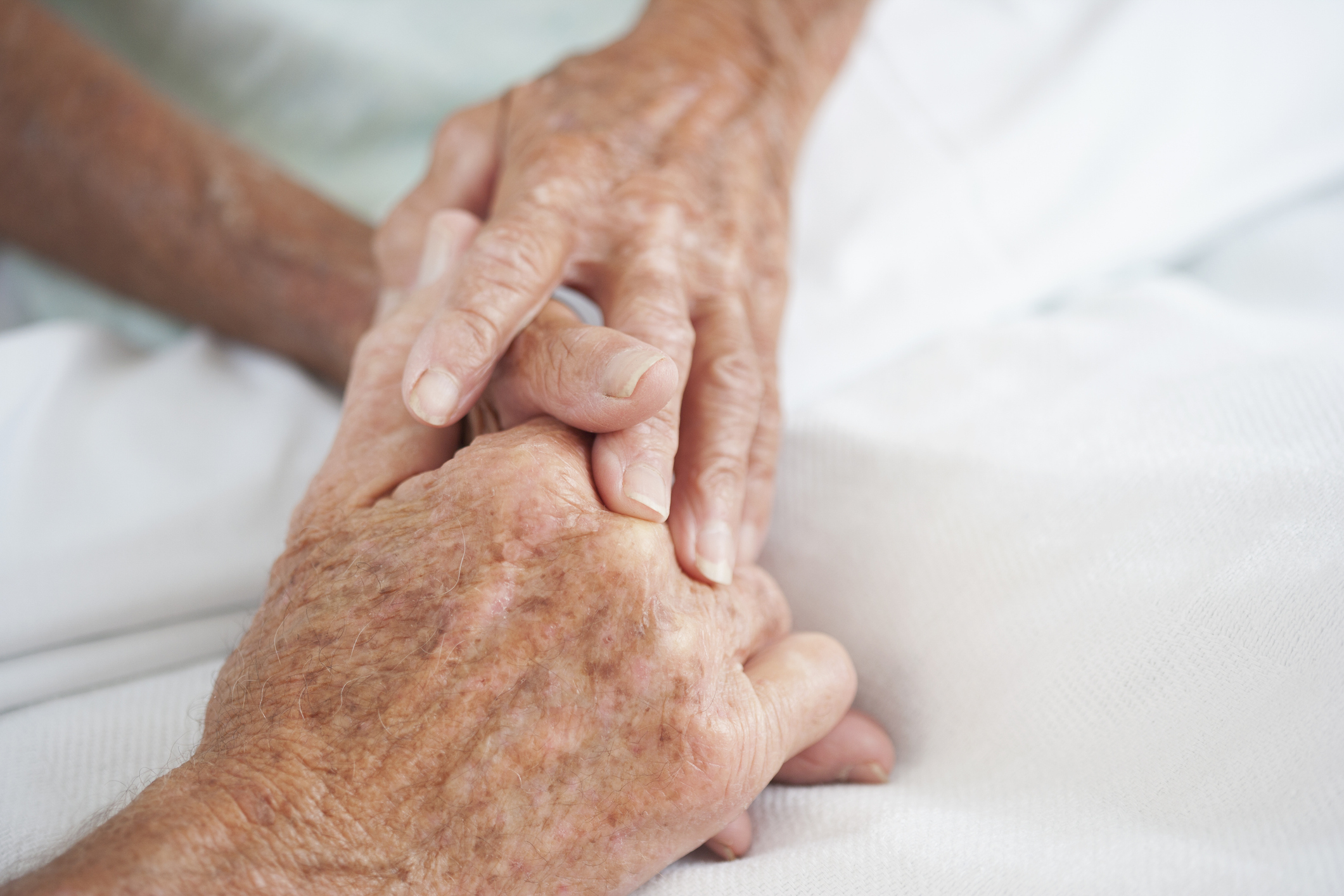 A close-up of a younger person&#x27;s hand holding an elderly person&#x27;s hand, offering comfort or support