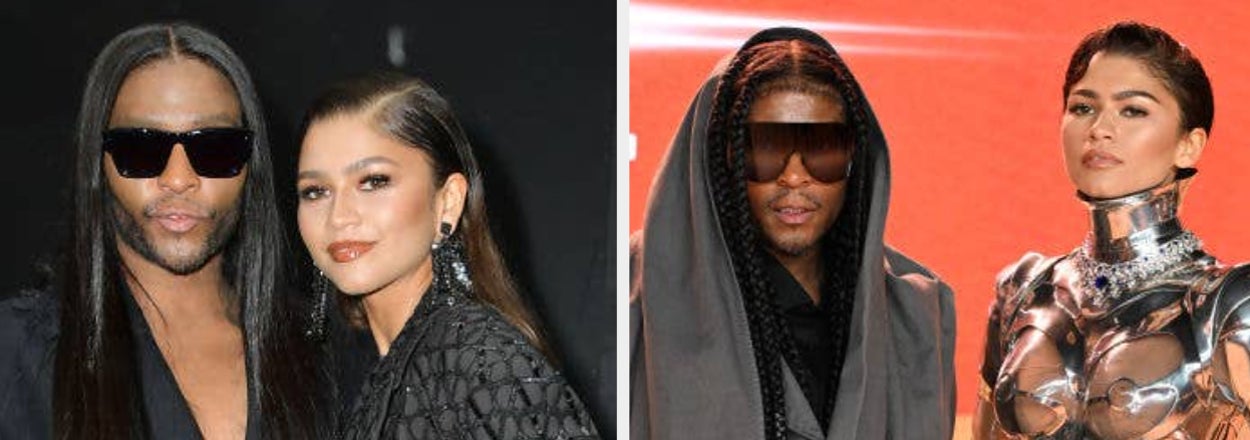 Two individuals posing, one in a metallic structured outfit, the other in black with a hood. They're at a celebrity event