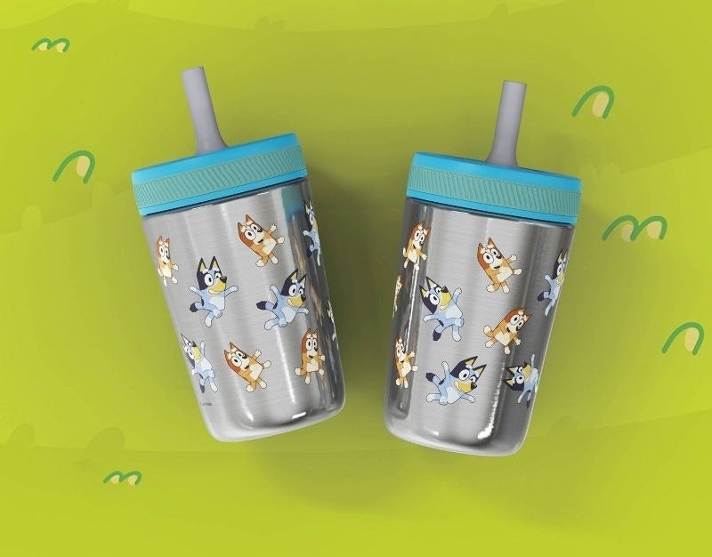 Two children&#x27;s sippy cups with cartoon dog print and silicone straws, ideal for kids&#x27; drinkware