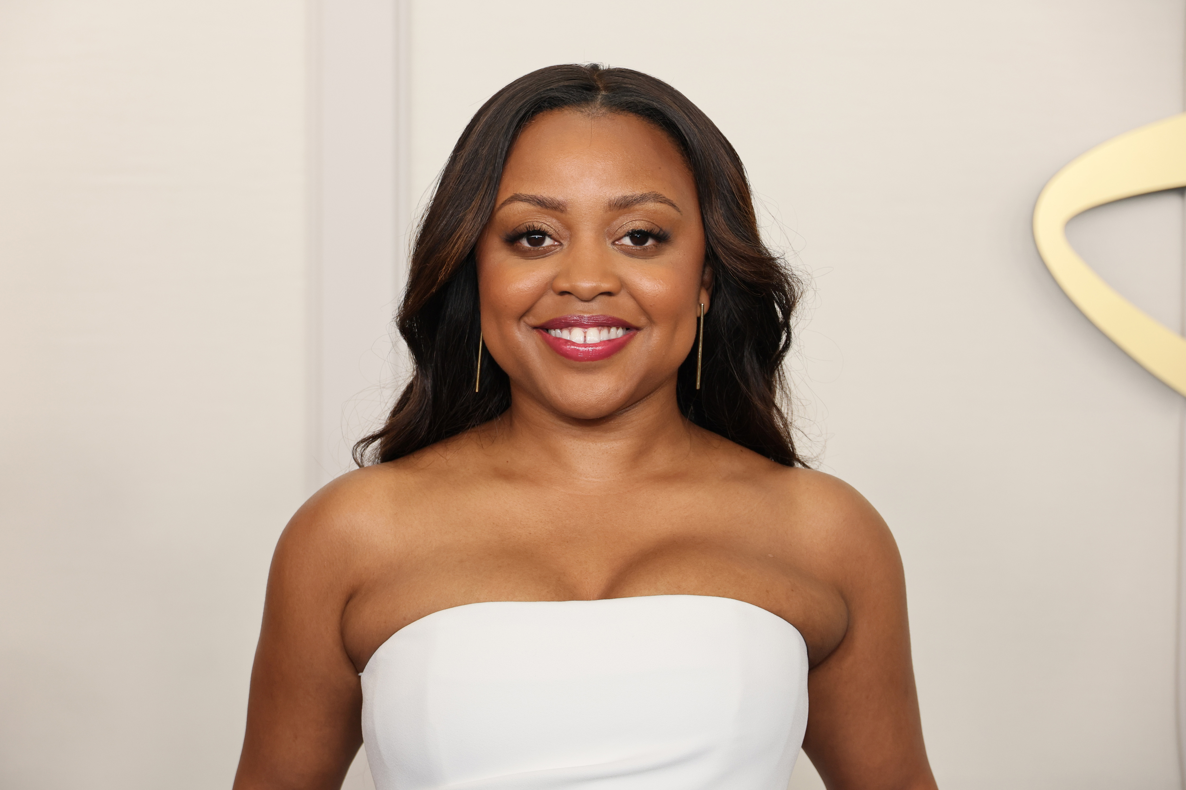 Quinta Brunson in a strapless white gown, smiling at a formal event