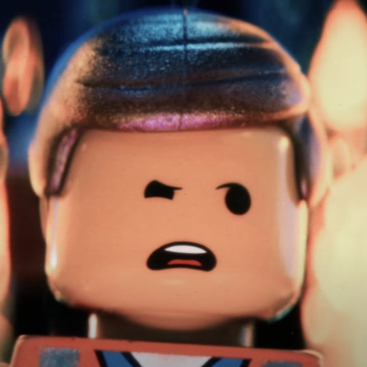 Lego character Emmet from "The Lego Movie" stands with a concerned expression, surrounded by a blurred fiery background