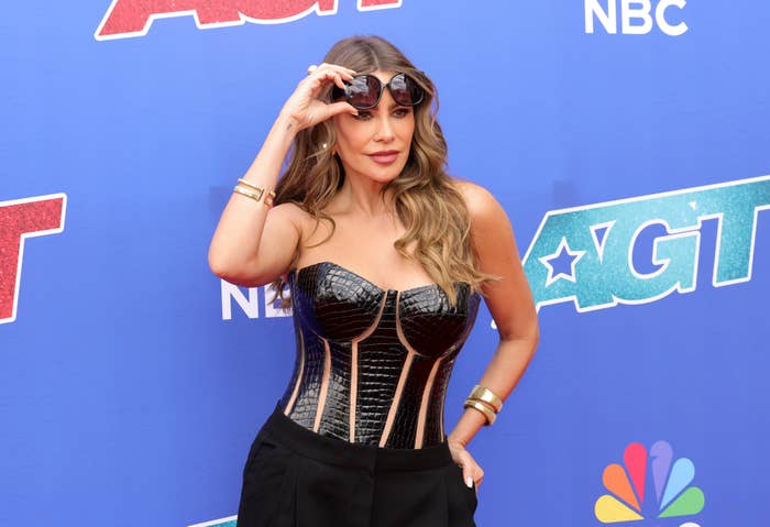 Sofia Vergara poses on the red carpet in a strapless, structured black top with pants at an America&#x27;s Got Talent event backdrop