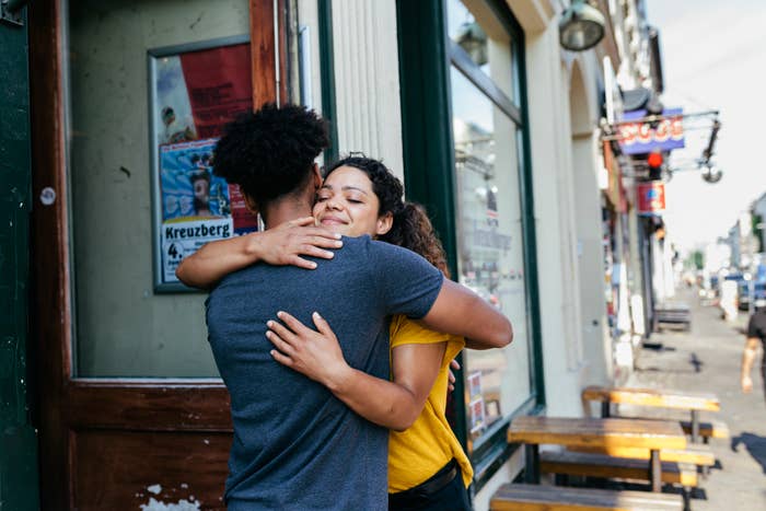 A couple embraces warmly outside of a building on a city street, showing affection and happiness