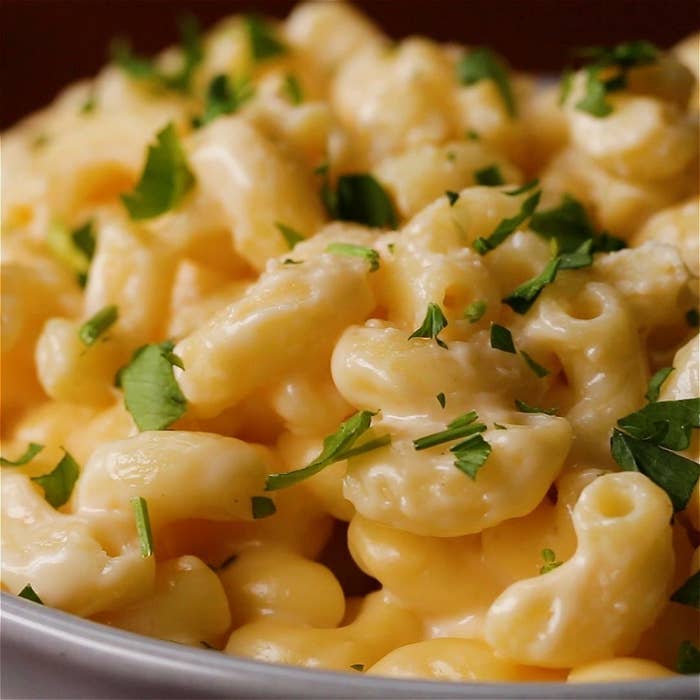 Close-up of a bowl of creamy macaroni and cheese garnished with chopped parsley