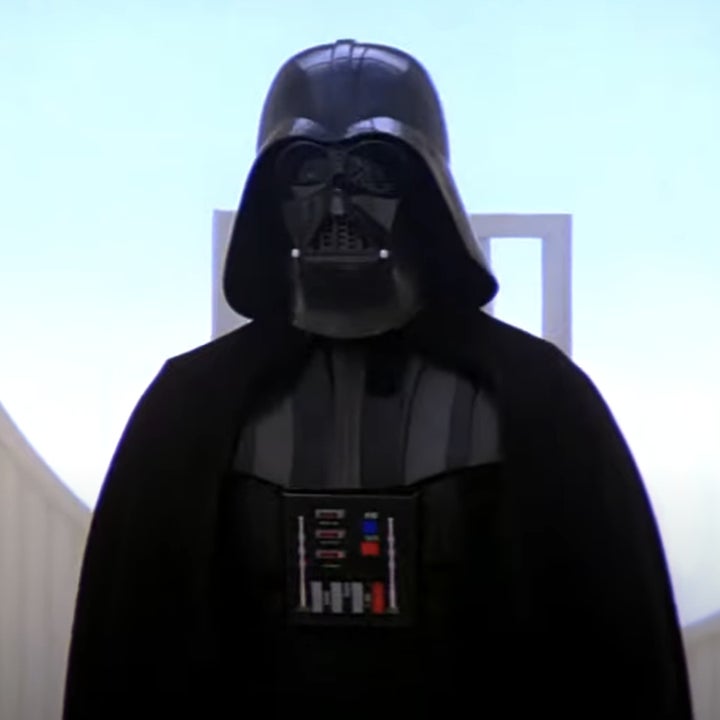 Darth Vader, dressed in his iconic black armor and cape with a mechanical chest panel, stands in a sci-fi setting
