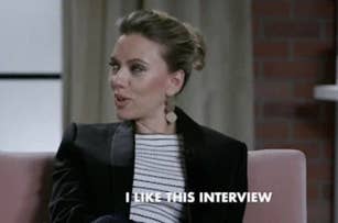 Scarlett Johansson in a striped top and black blazer, sitting on a couch, saying "I like this interview."