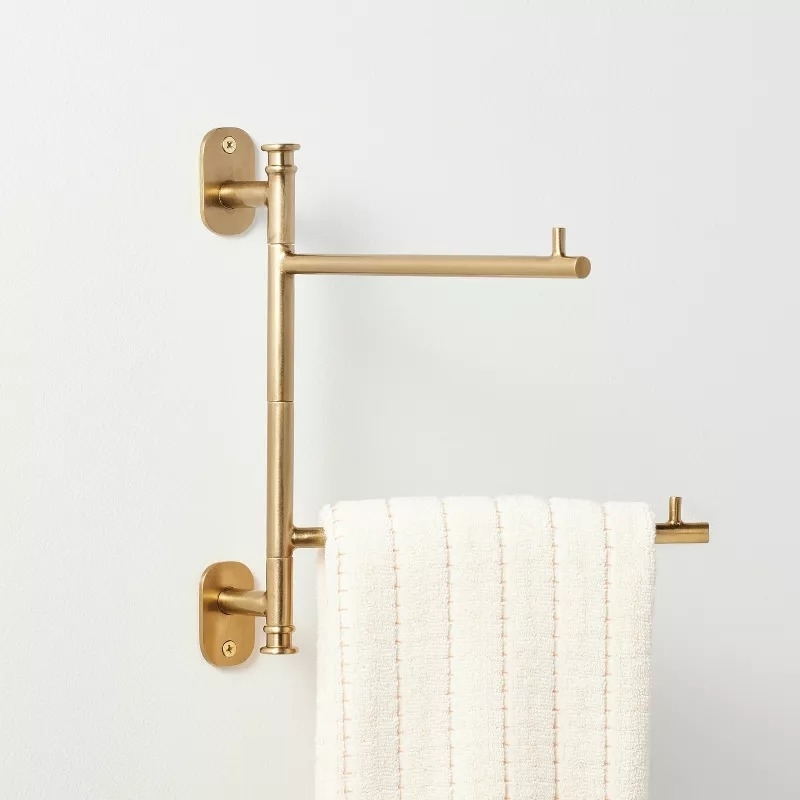 Gold swing arm towel bar with a white towel hanging