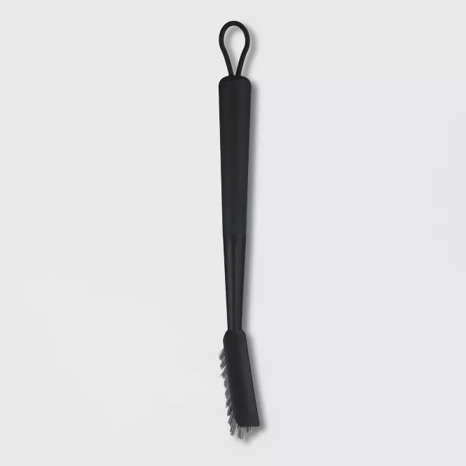 Long-handled scrub brush with a loop for hanging, featuring bristles at one end for cleaning. Ideal for hard-to-reach areas