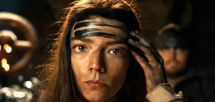 Anya Taylor-Joy applying black makeup to her forehead in a scene from "Furiosa: A Mad Max Saga"
