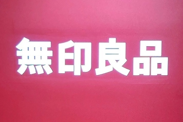 無印良品の店舗入口の看板。背景は赤色。