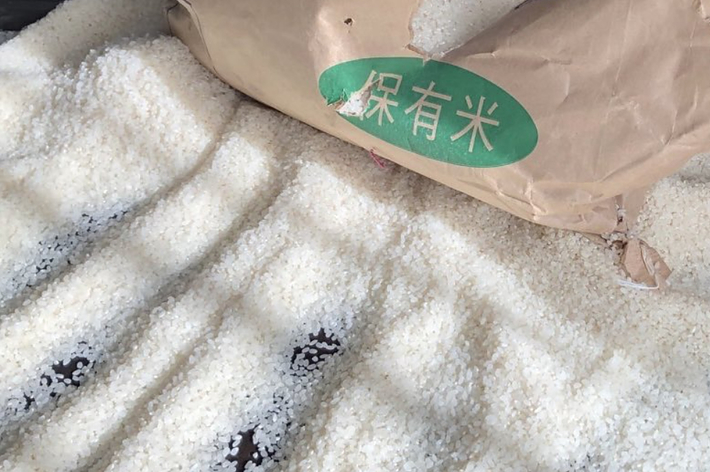 米袋が破れて床に米がこぼれている場面。