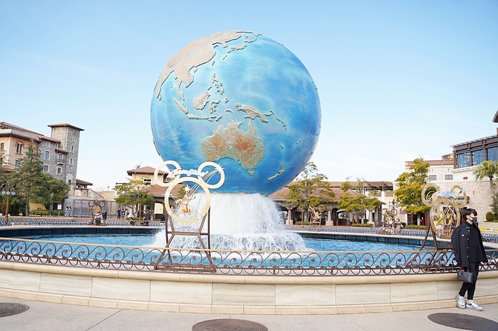 大きな地球儀のある噴水の前に一人の人が立っています。