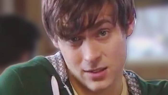 A person with medium-length hair looks directly at the camera with a slight smile in a casual setting