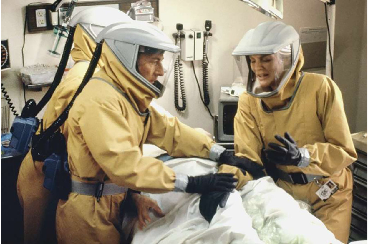 Dustin Hoffman and Rene Russo are in a hospital room, dressed in full-body hazmat suits, examining a patient lying on a bed