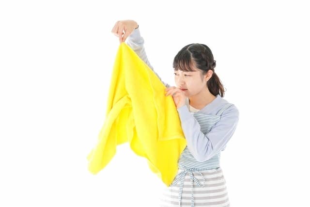 女性が黄色のタオルを広げている様子。