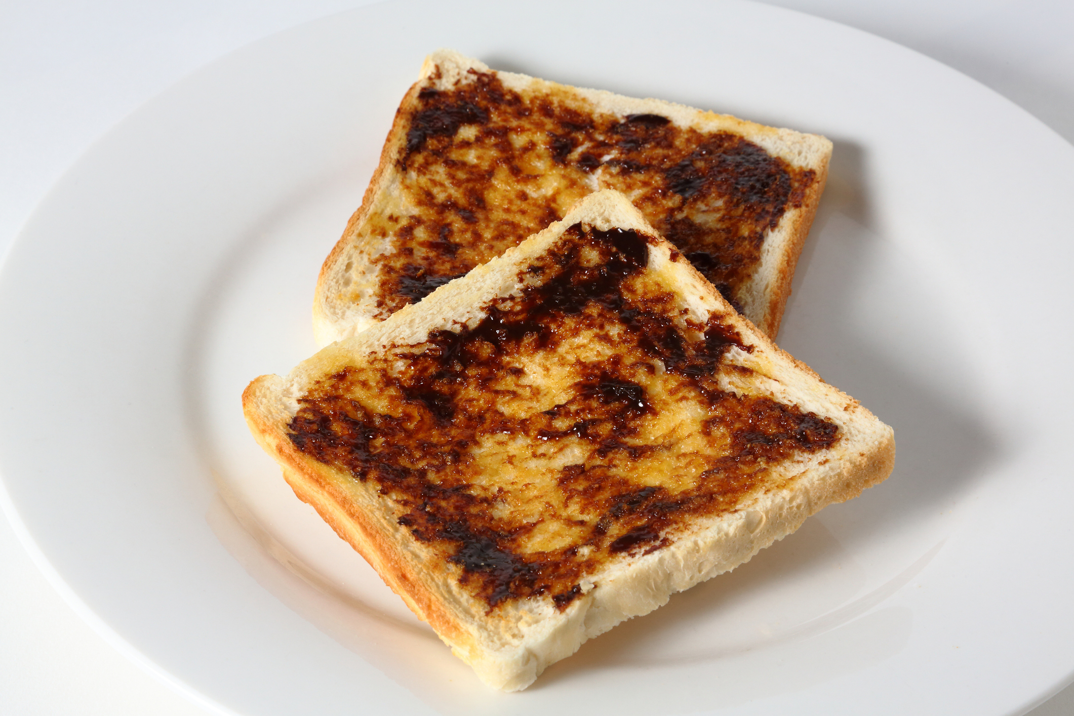 Two slices of toast with a spread on a white plate