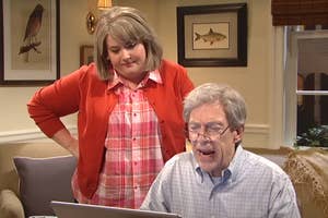Cecily Strong helps Steve Martin at a computer. They appear to be in a home setting, with framed pictures on the wall behind them