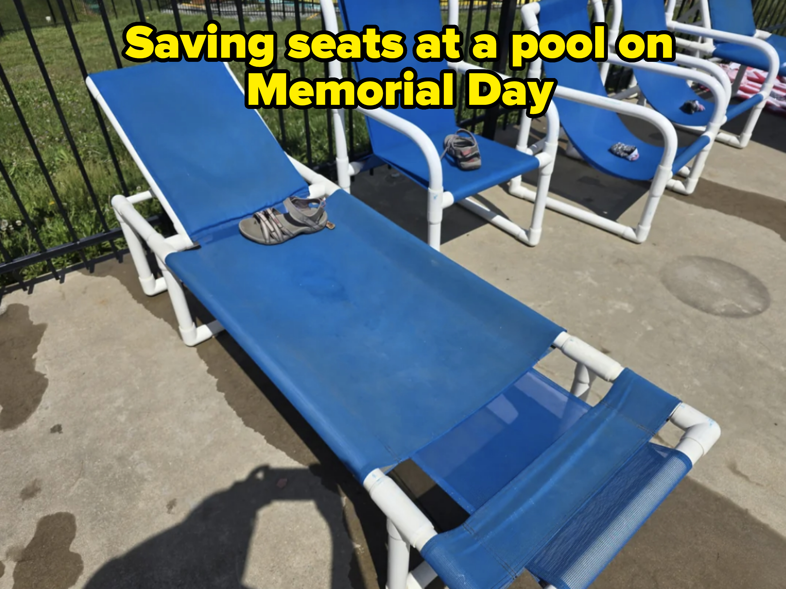 Blue lounge chairs poolside. One chair has sandals placed on it. No people are present in the image