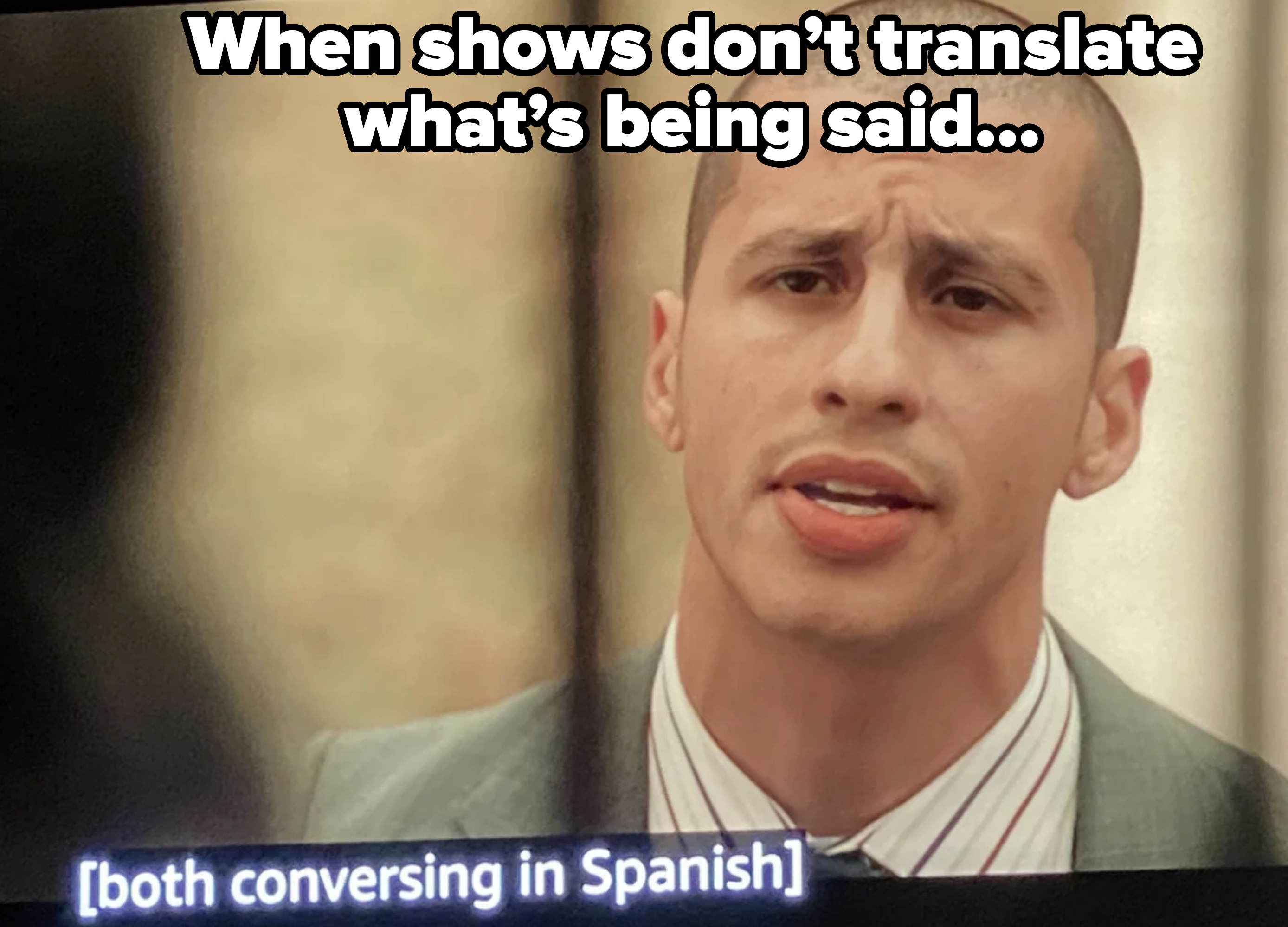 Man in a suit, conversing in Spanish with subtitles indicating "both conversing in Spanish."