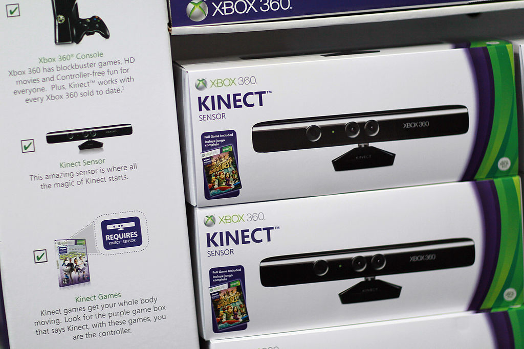 Xbox 360 Kinect sensor boxes on display showcasing features and package contents; "Requires Kinect Sensor" note on a game box adjacent to sensors