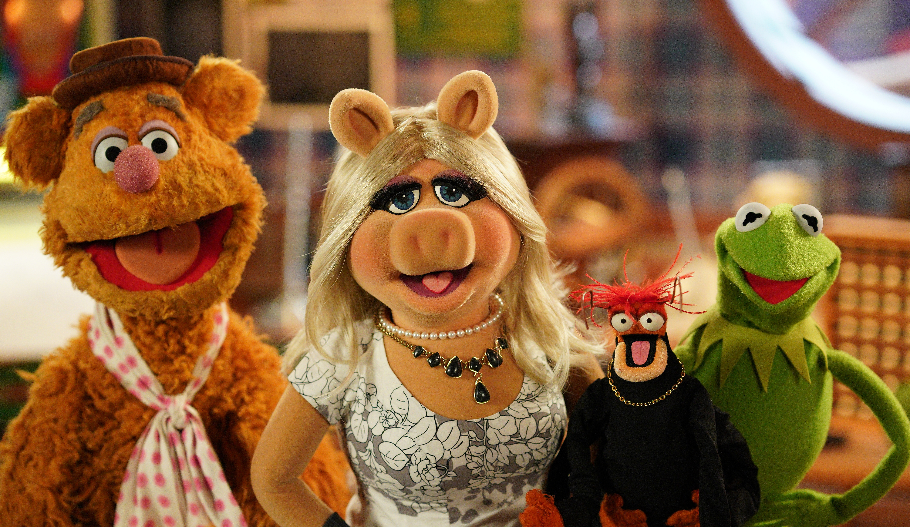 Fozzie Bear, Miss Piggy, Pepe the King Prawn, and Kermit the Frog are posing together, each showcasing their unique and recognizable styles