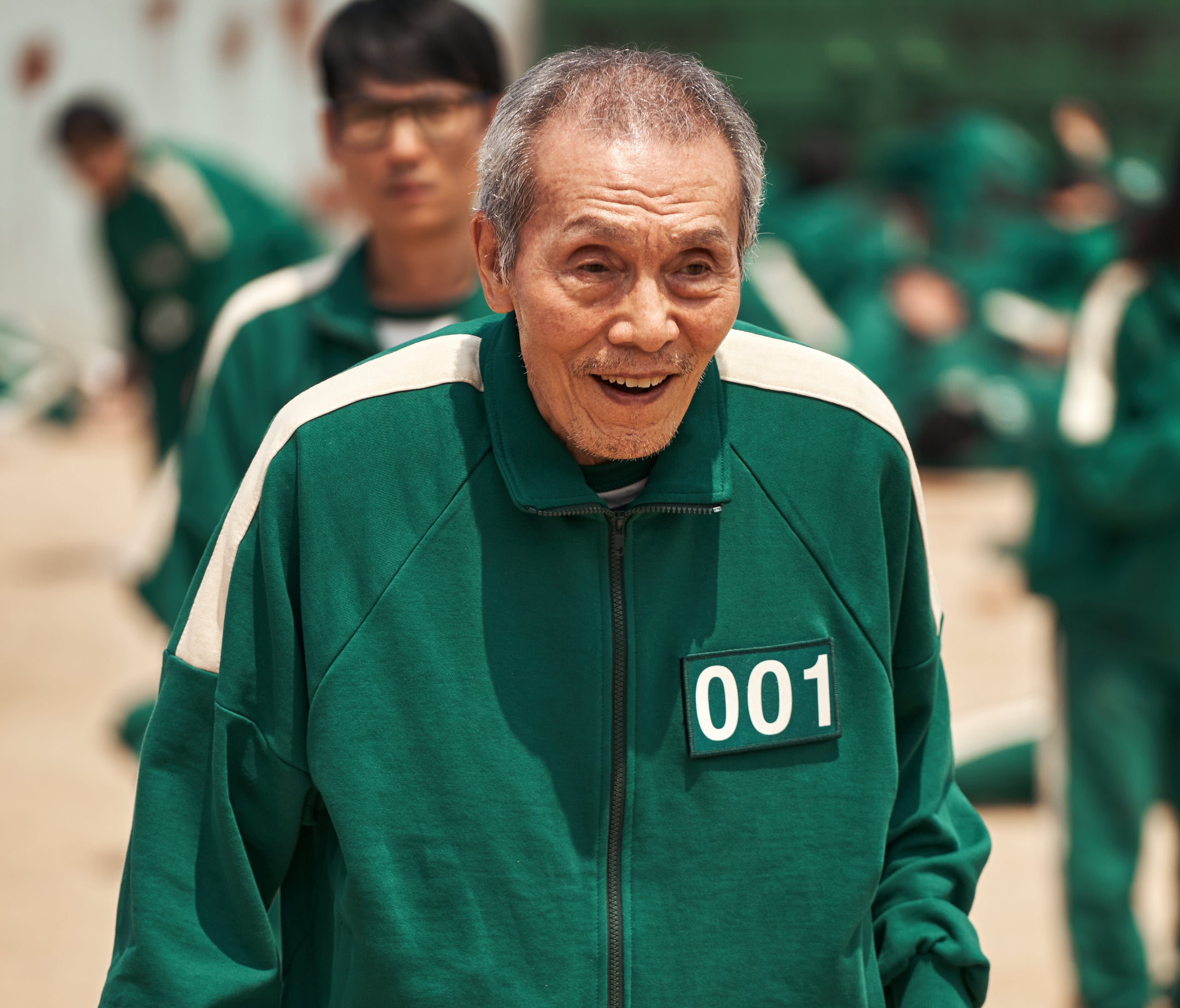 Oh Yeong-su in a green tracksuit with number 001, in a scene from what appears to be a dramatic outdoor activity