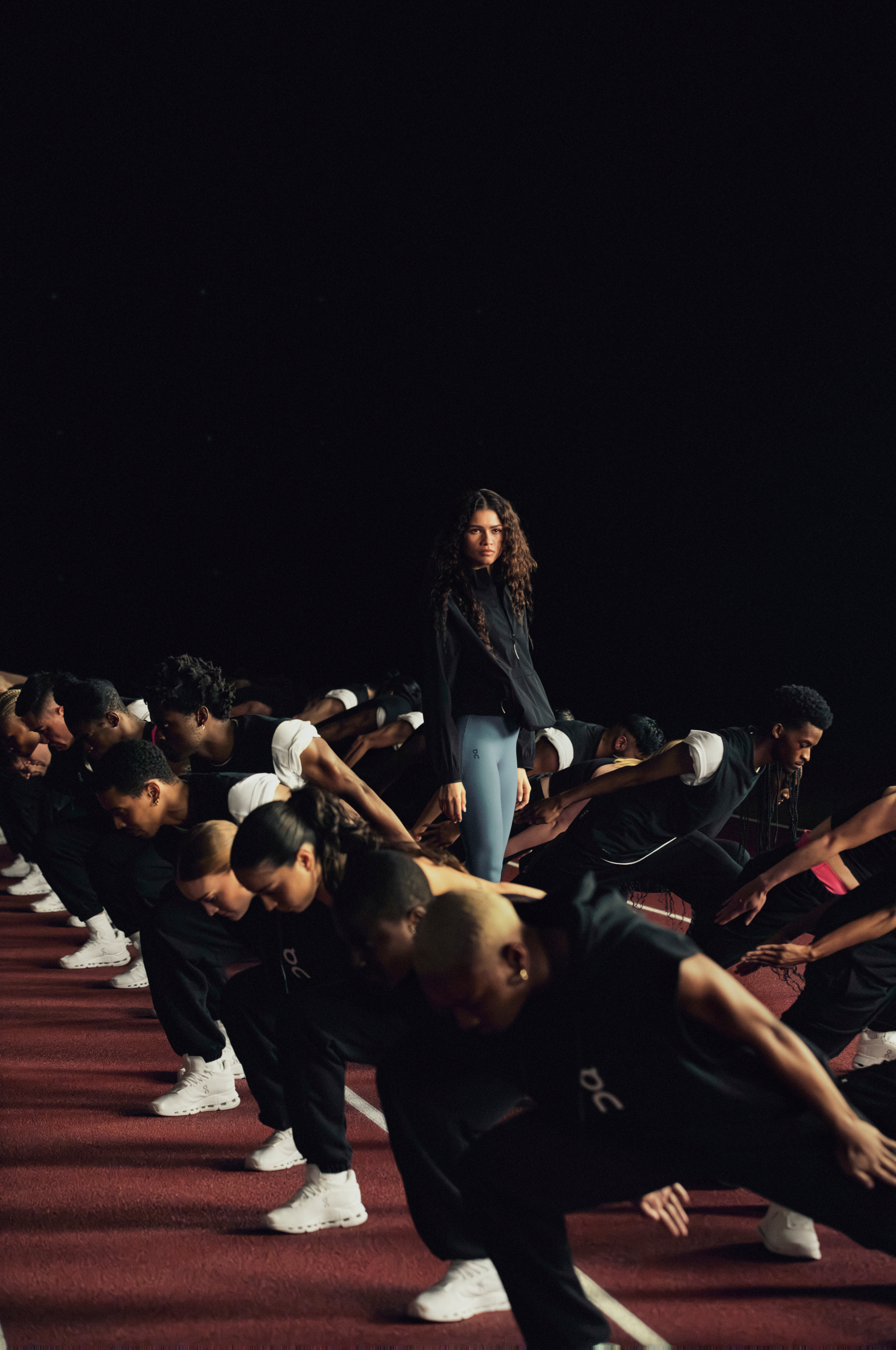 Zendaya stands in the center while a group of dancers in black and white athletic wear perform synchronized moves on either side