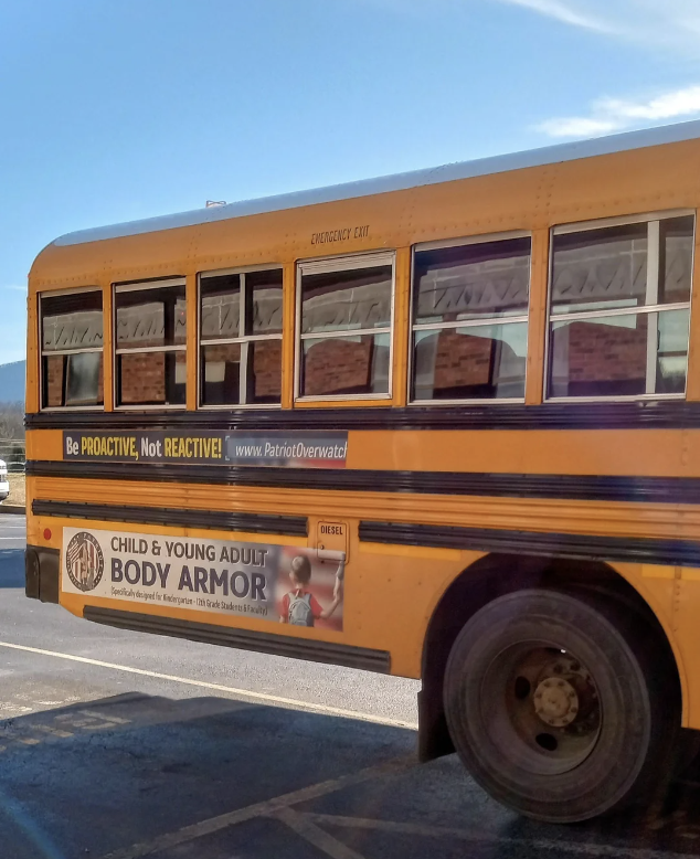Side view of a yellow school bus with two s; one reads "Be PROACTIVE, Not REACTIVE!" while another promotes child and young adult body armor
