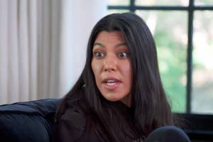 Kourtney Kardashian in a casual conversation, wearing a dark sweatshirt, indoors with a window in the background. The scene is from an "E!" network feature