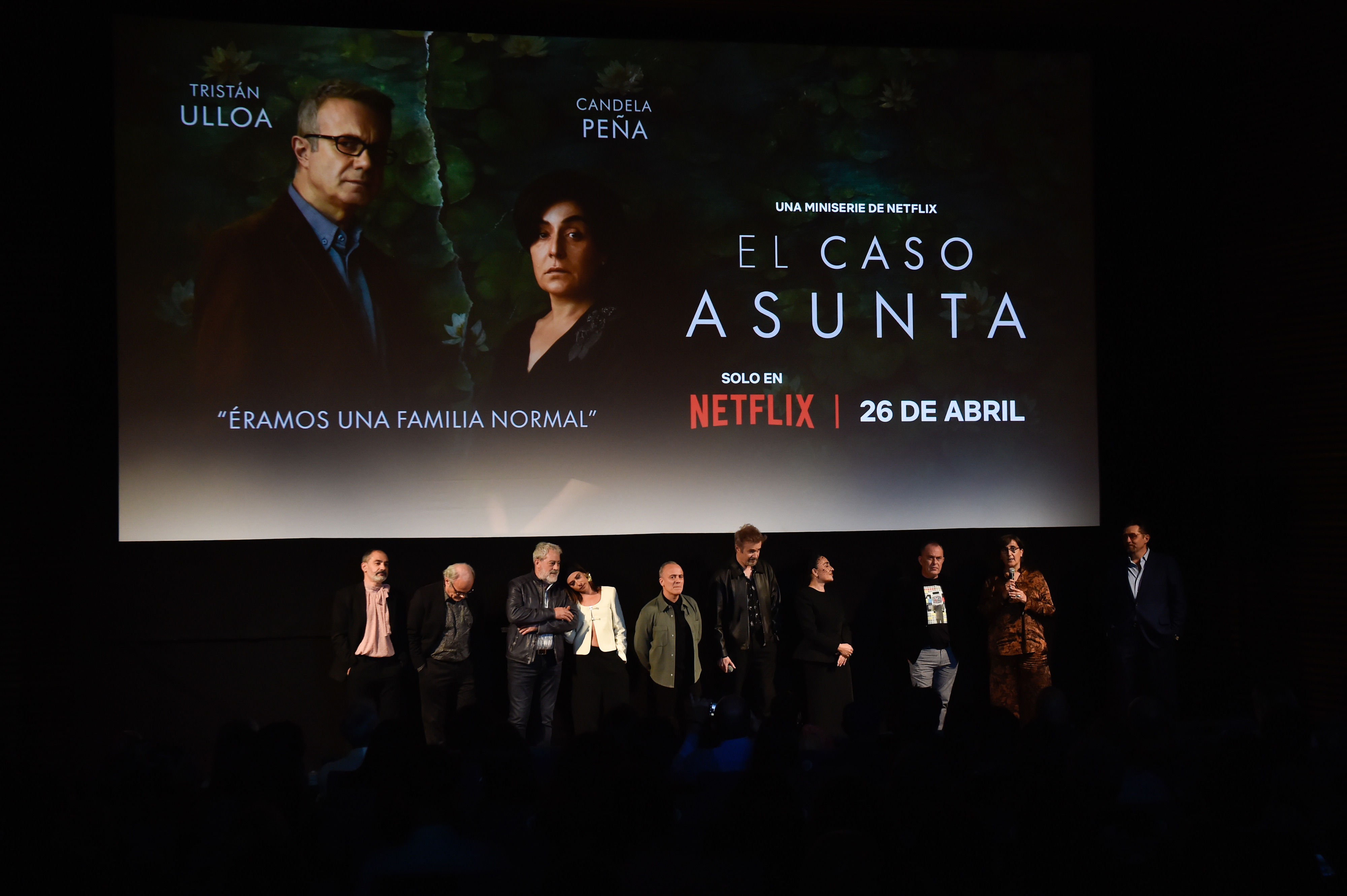 Cast and crew on stage at a premiere event for the Netflix documentary, El Caso Asunta, with Tristán Ulloa and Candela Peña shown on the screen behind them