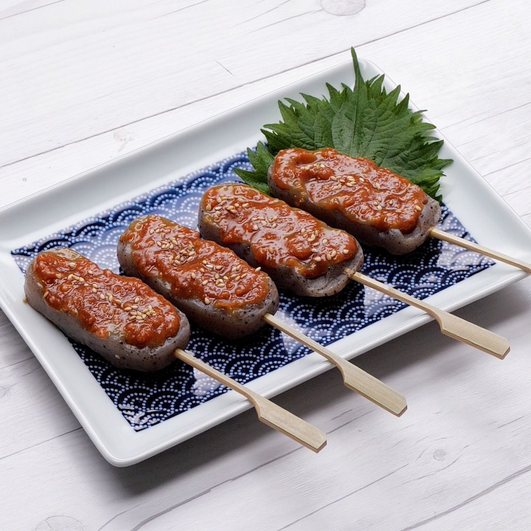 お皿に盛られた、串に刺したみそ田楽が4本、しその葉と一緒に並んでいます。