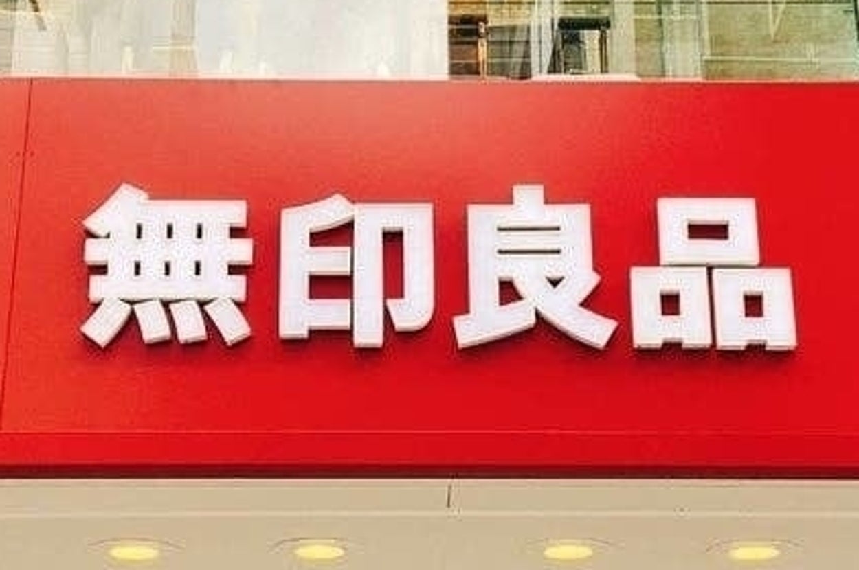 The image shows a storefront with large white Japanese characters on a red sign, which translate to "MUJI", a well-known retail company