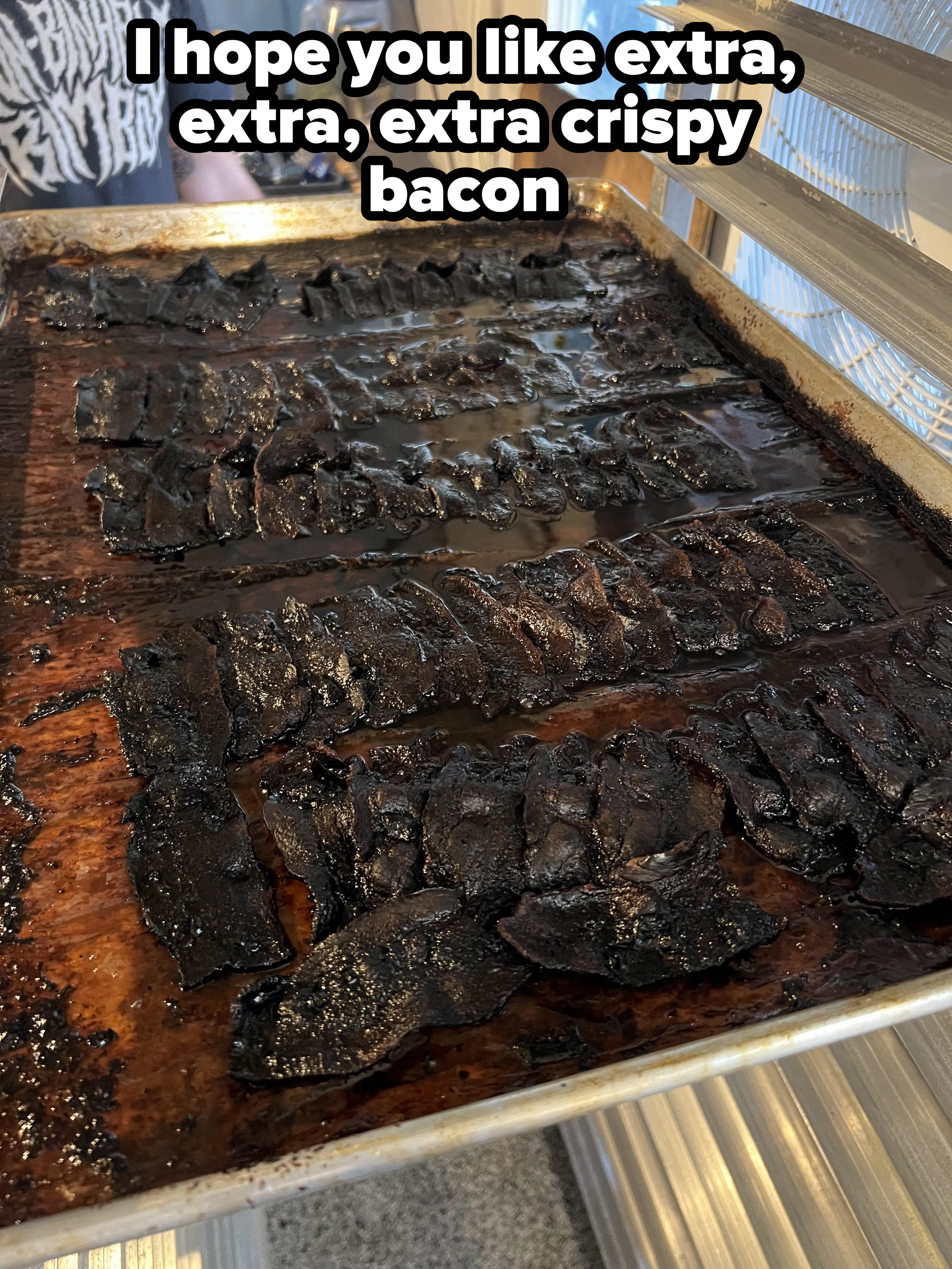 A tray of burnt bacon strips on a kitchen counter
