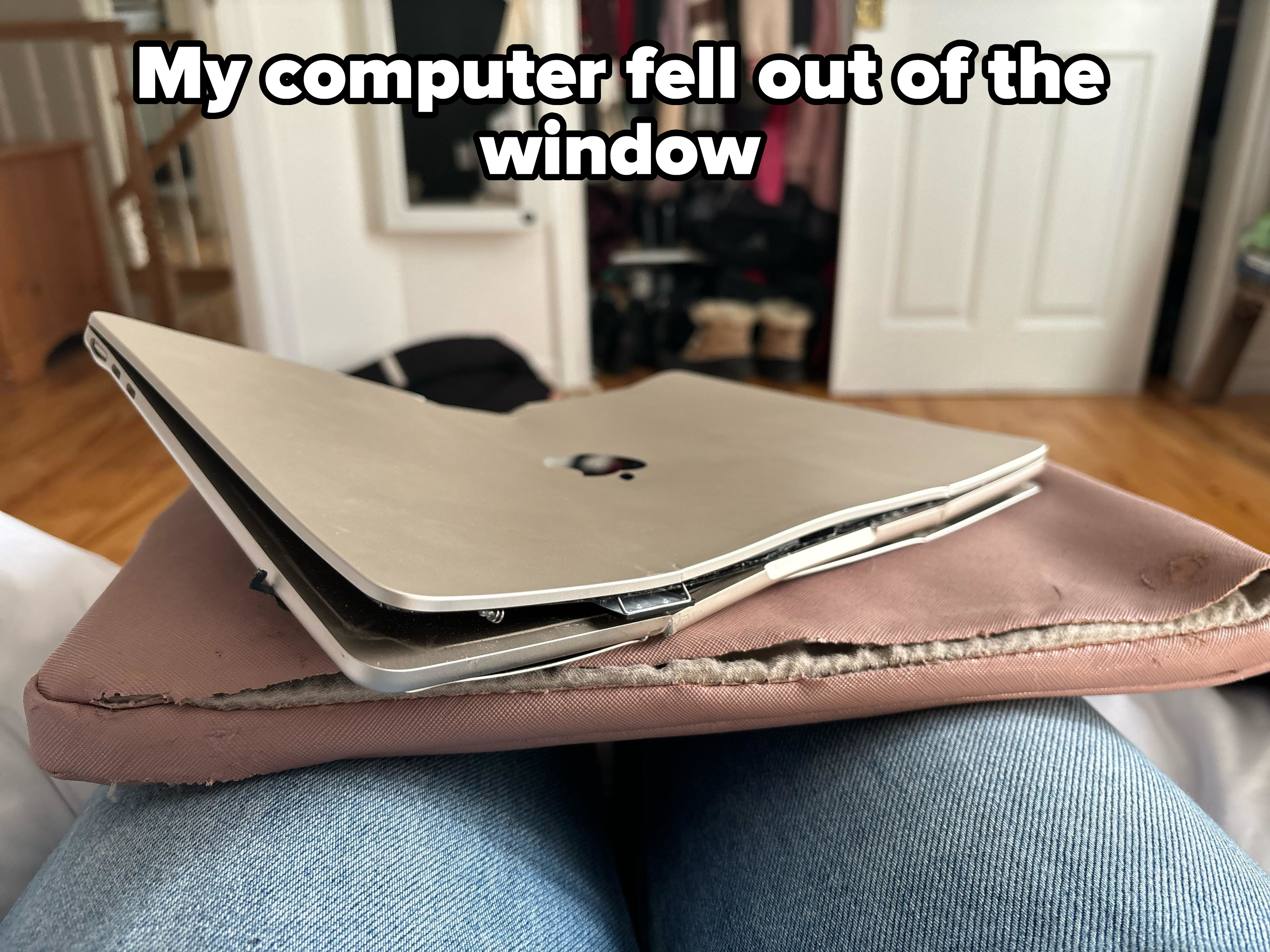 Damaged laptop with bent screen and keyboard, resting on a person&#x27;s lap