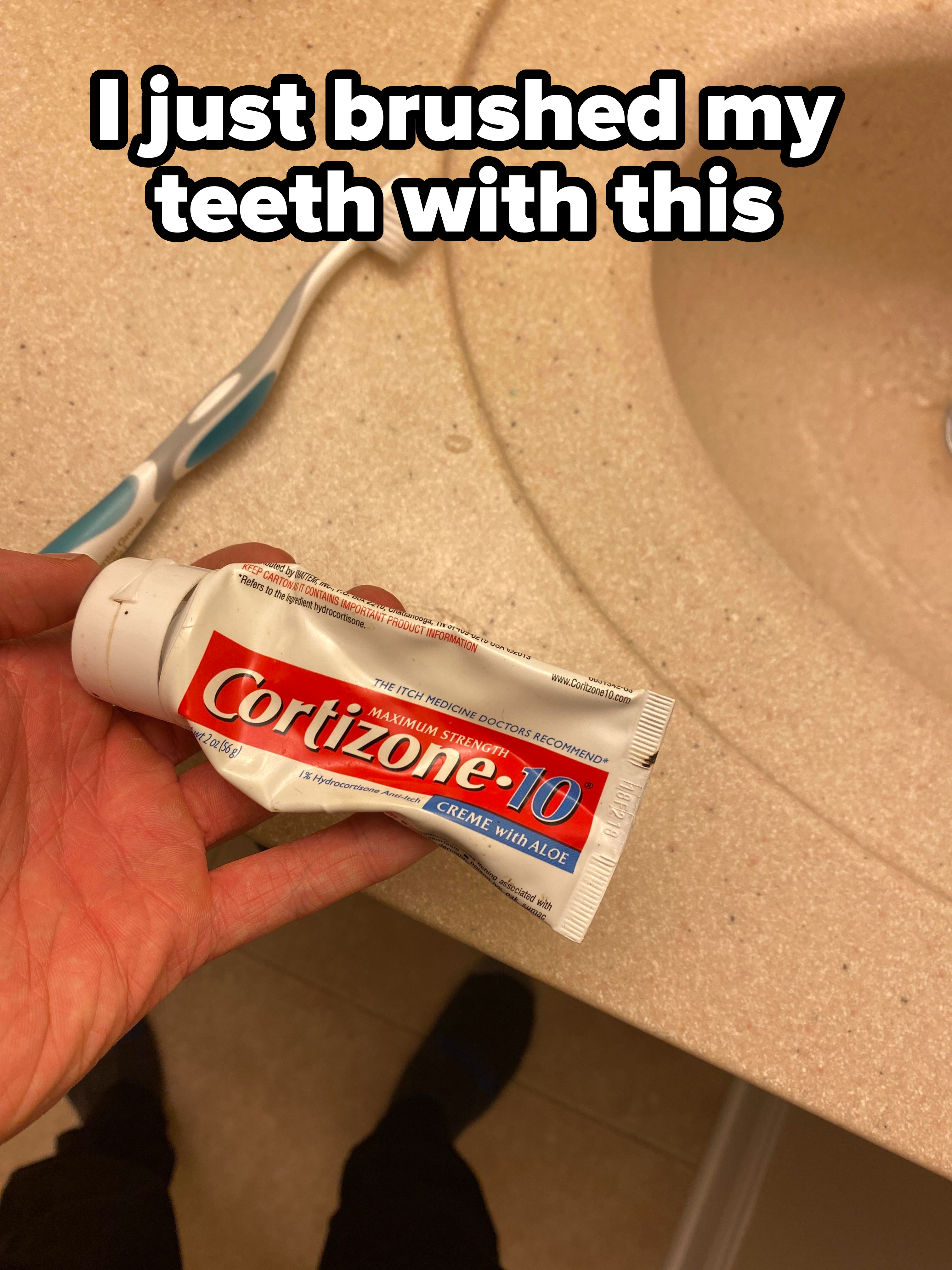 Hand holding a squeezed tube of Cortizone-10 cream above a sink with a toothbrush to the side