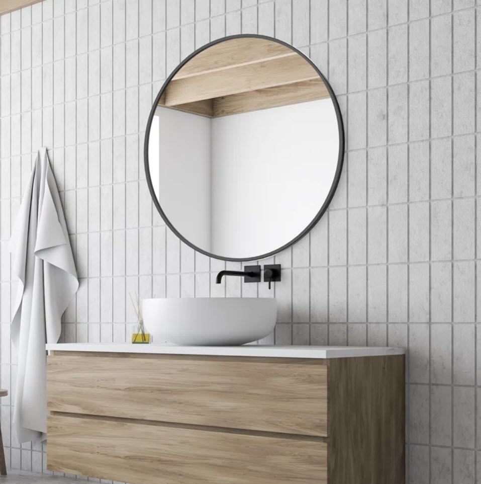 Modern bathroom with a round mirror above a wooden vanity