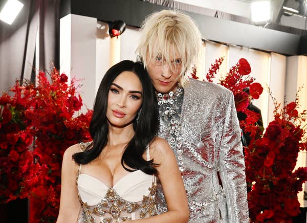 Kim Kardashian in a bejeweled gown with plunging neckline and a person with blond hair in a glittery suit, standing together