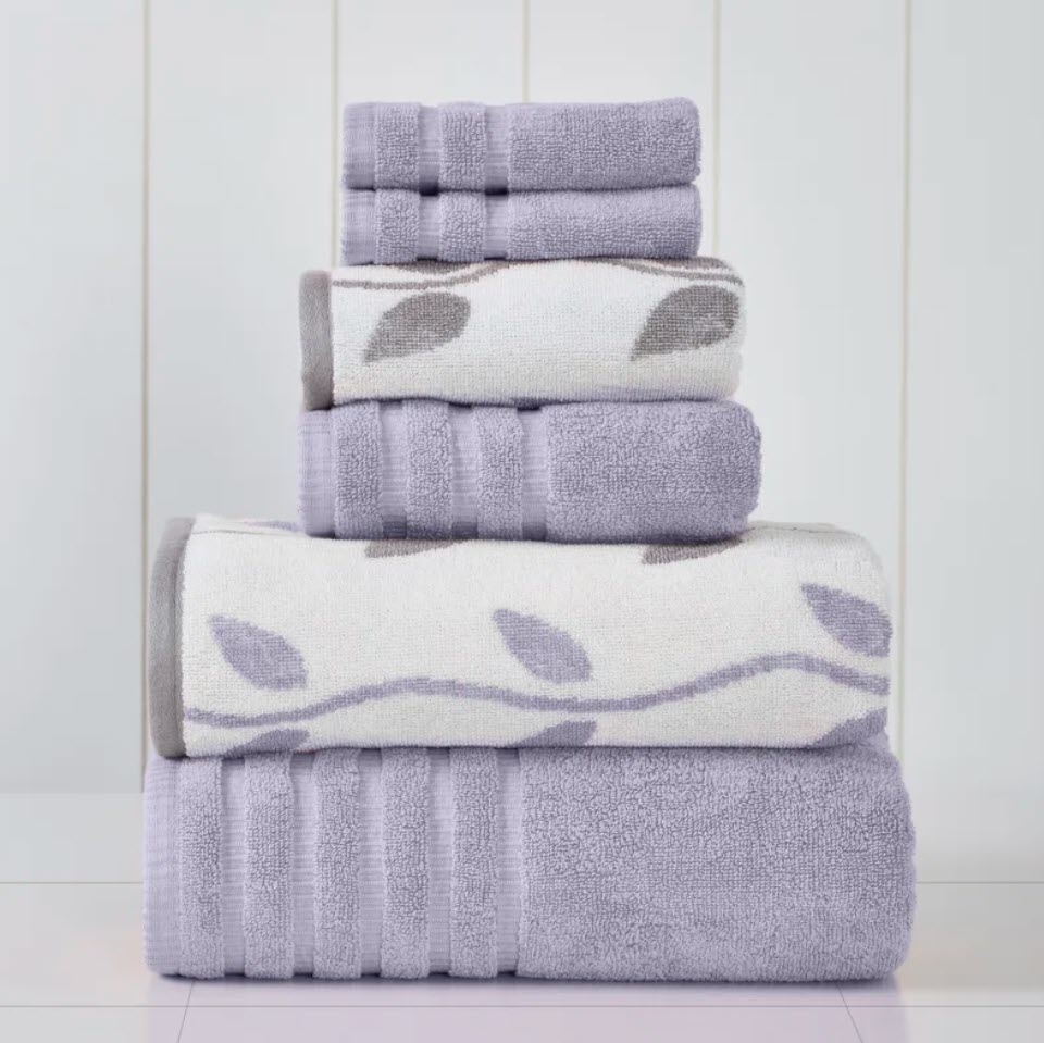Stack of various-sized plush towels with a leaf pattern on one. Ideal for bathroom linens