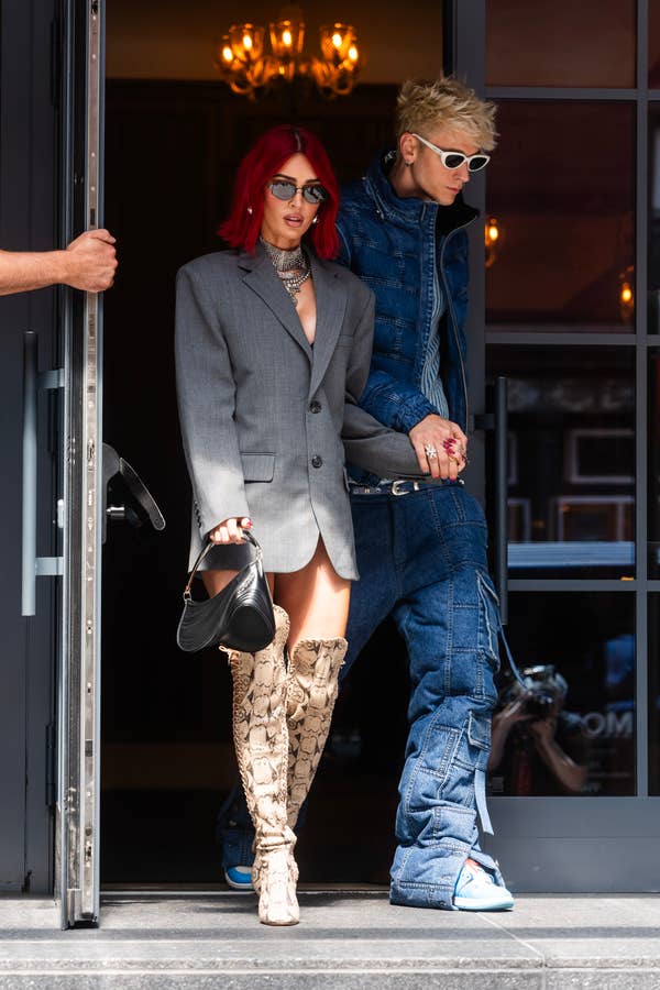 Woman in blazer and knee-high boots with man in denim exits building