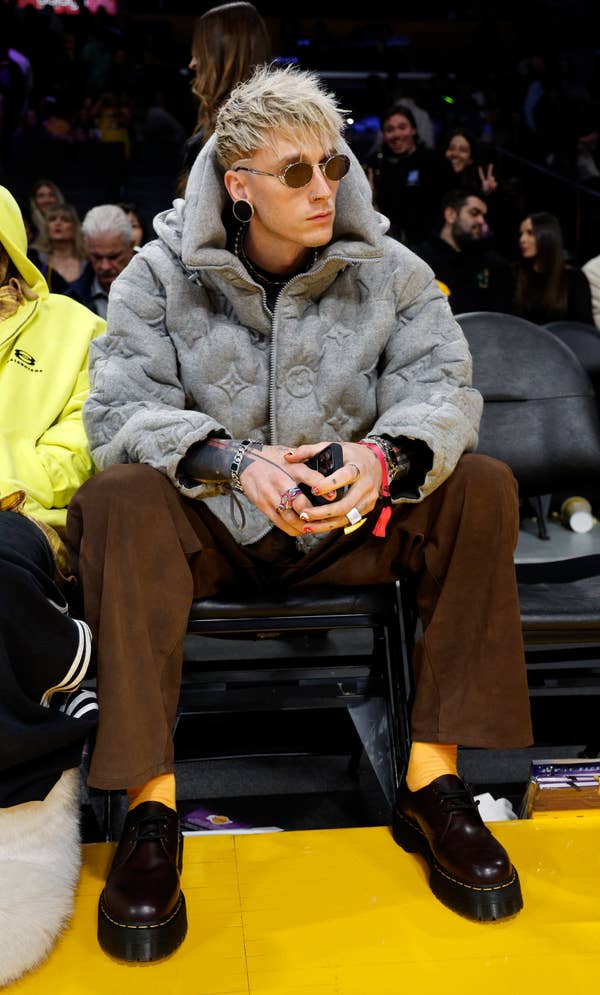 Person in hooded jacket and sunglasses sitting courtside