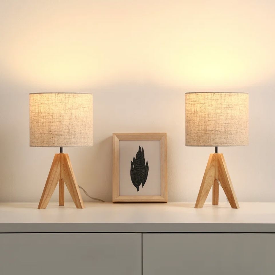 Two symmetrically placed table lamps flank a framed leaf print, creating a warm ambiance suitable for home decor