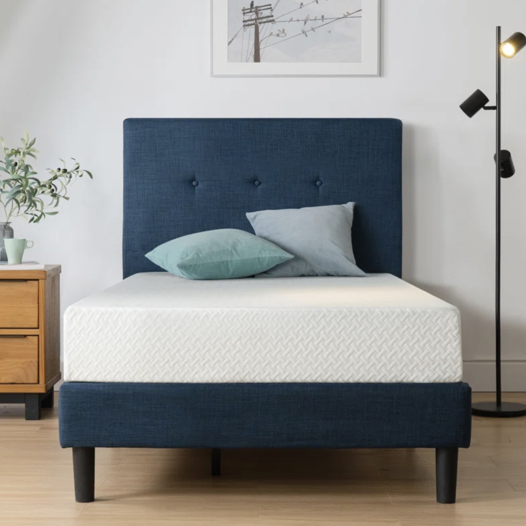 Navy upholstered bed with white zigzag-patterned bedding in a minimalist bedroom setup