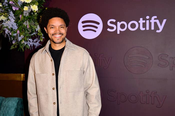 Trevor Noah smiling, wearing a casual jacket, at a Spotify event
