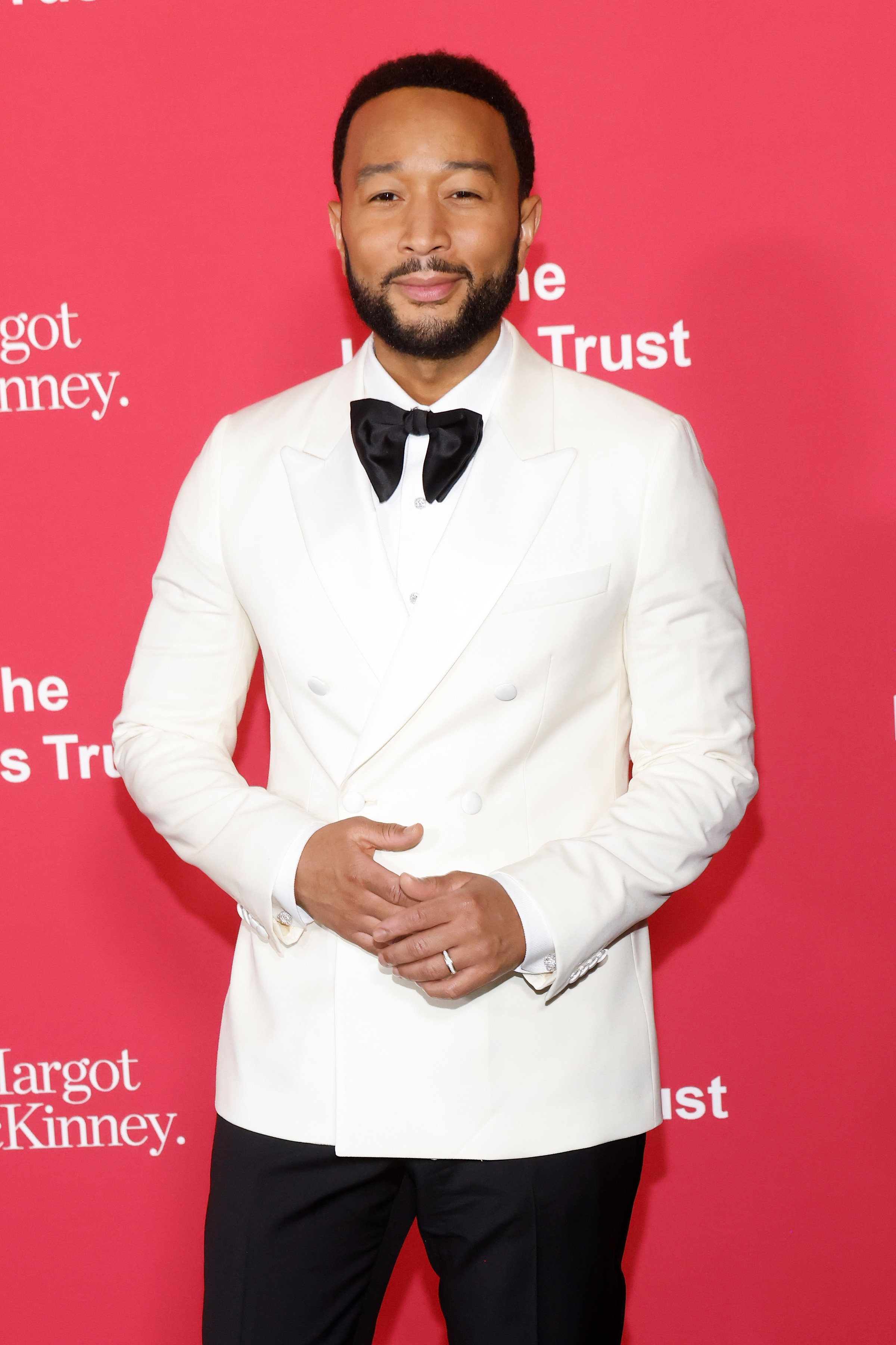 John Legend in a white tuxedo with black lapels, posing at an event
