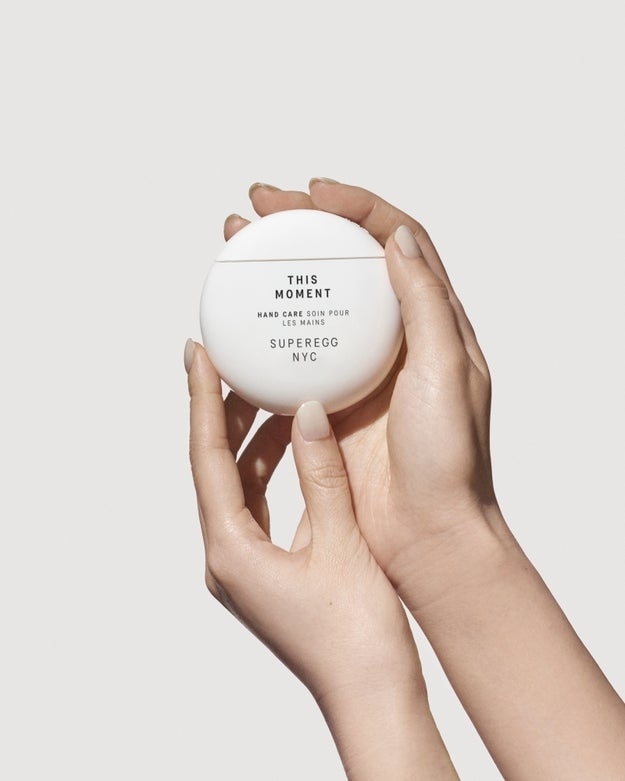 Hands holding a Superegg skincare product against a plain backdrop