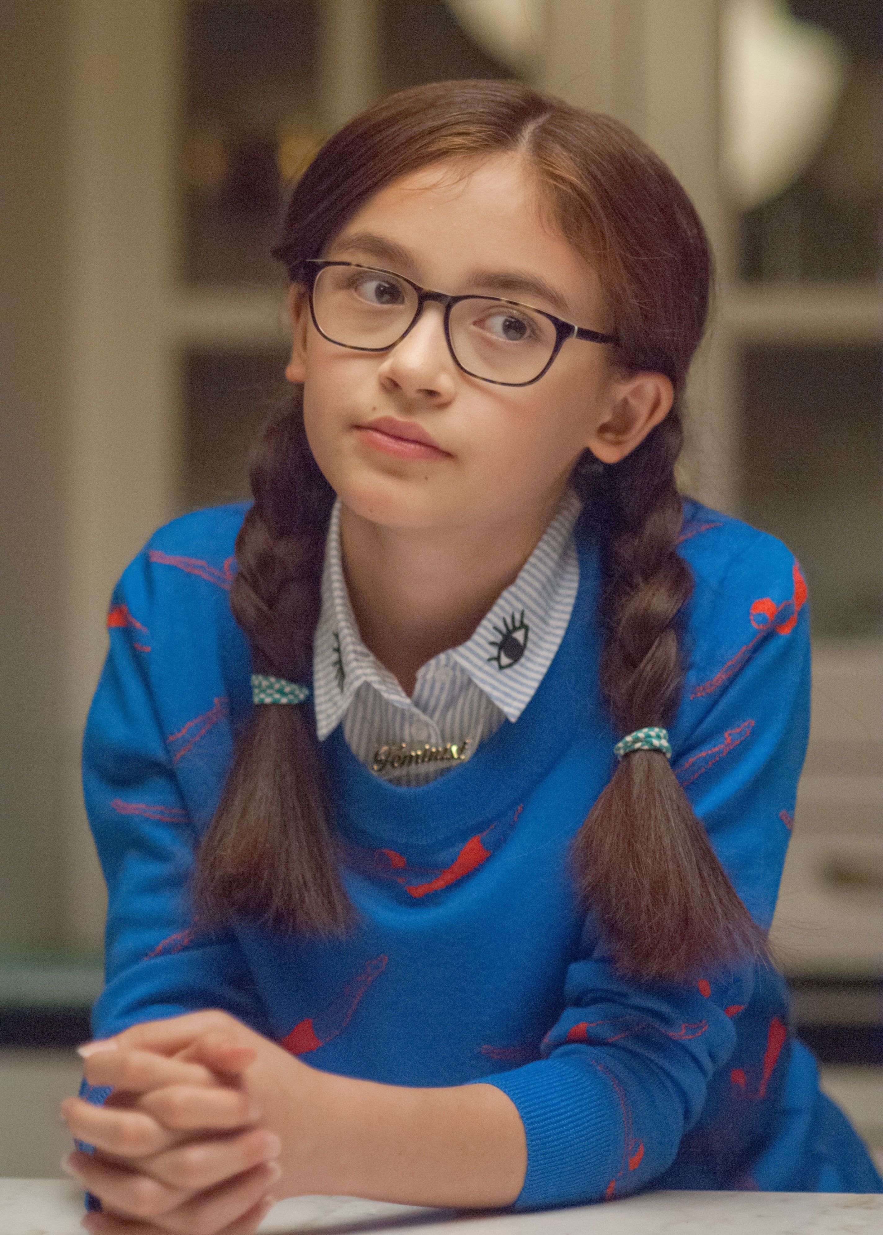 Anna Cathcart with braided hair wearing glasses and a patterned sweater